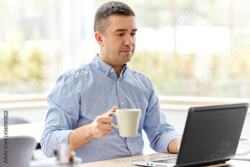 remote job, business and people concept - middle-aged man with laptop computer working at home office and drinking coffee