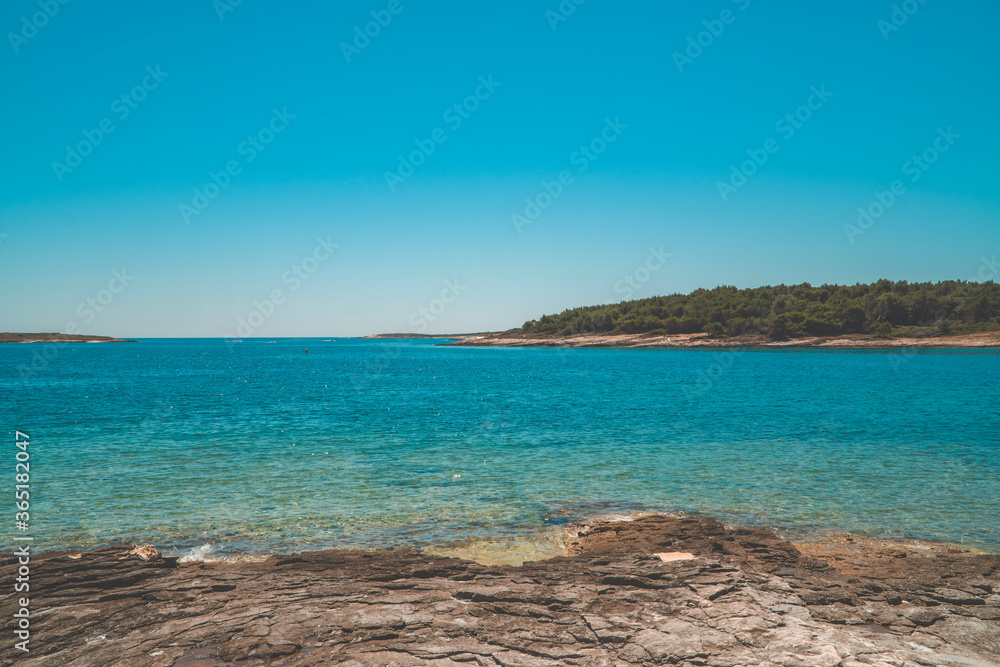 Fototapeta premium Stony rock beach with beautiful turquoise waters in Kamenjak, Istria, Croatia