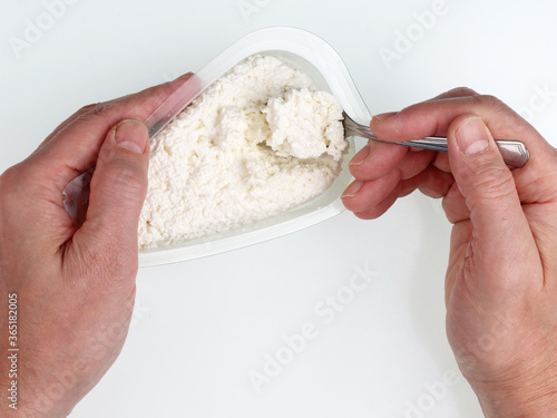 Fotografi Old man eats cottage cheese from a plastic box