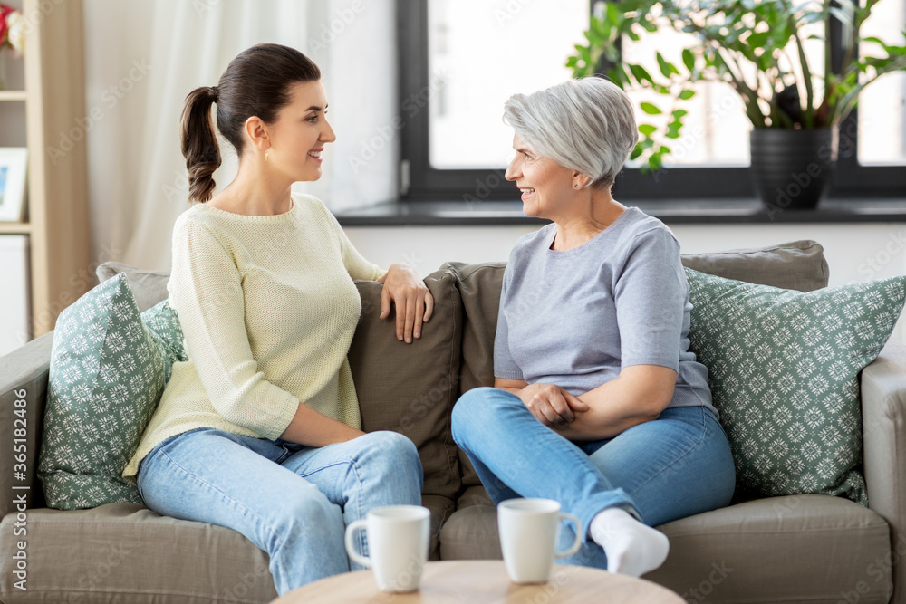 family, generation and people concept - happy smiling senior mother with adult daughter talking at home family, generation and people concept - happy smiling senior mother with adult daughter talking at home