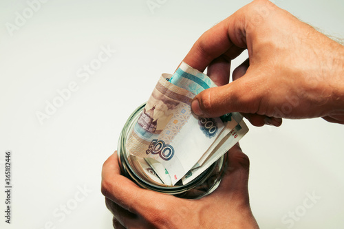 male hands hold a glass jar filled with paper money