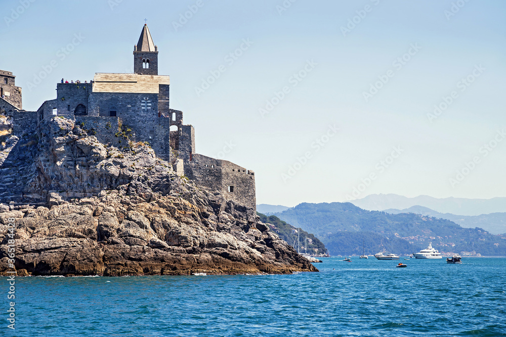 Picturesque view from sea the entrens to the Porto Venere with Doria castle and gothic church of St. Peter. Marina with yachts and boats on the background. Near Cinque Terre. Liguria, Italy. Picturesque view from sea the entrens to the Porto Venere with Doria castle and gothic church of St. Peter. Marina with yachts and boats on the background. Near Cinque Terre. Liguria, Italy.