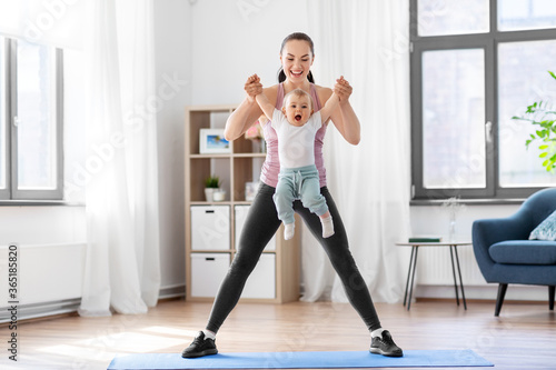 family  sport and motherhood concept - happy smiling mother with little baby exercising at home