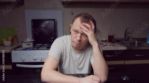 A man sitting motionless in the kitchen in the evening, depressed, crisis