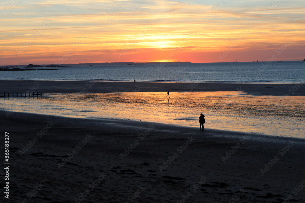 Romantic walk of people before sunset on the picturesque beach of Saint Malo. Brittany, France