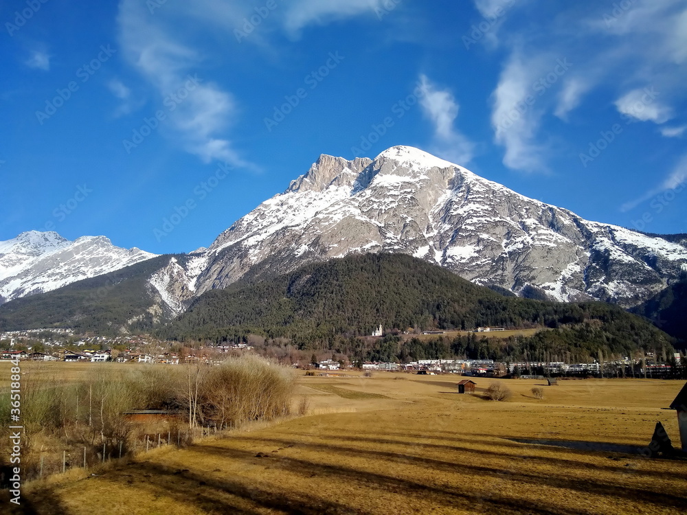 lange Schatten bei winterlichem Föhnwetter mit schneebedeckten Gipfeln in Telfs, Tirol, Österreich