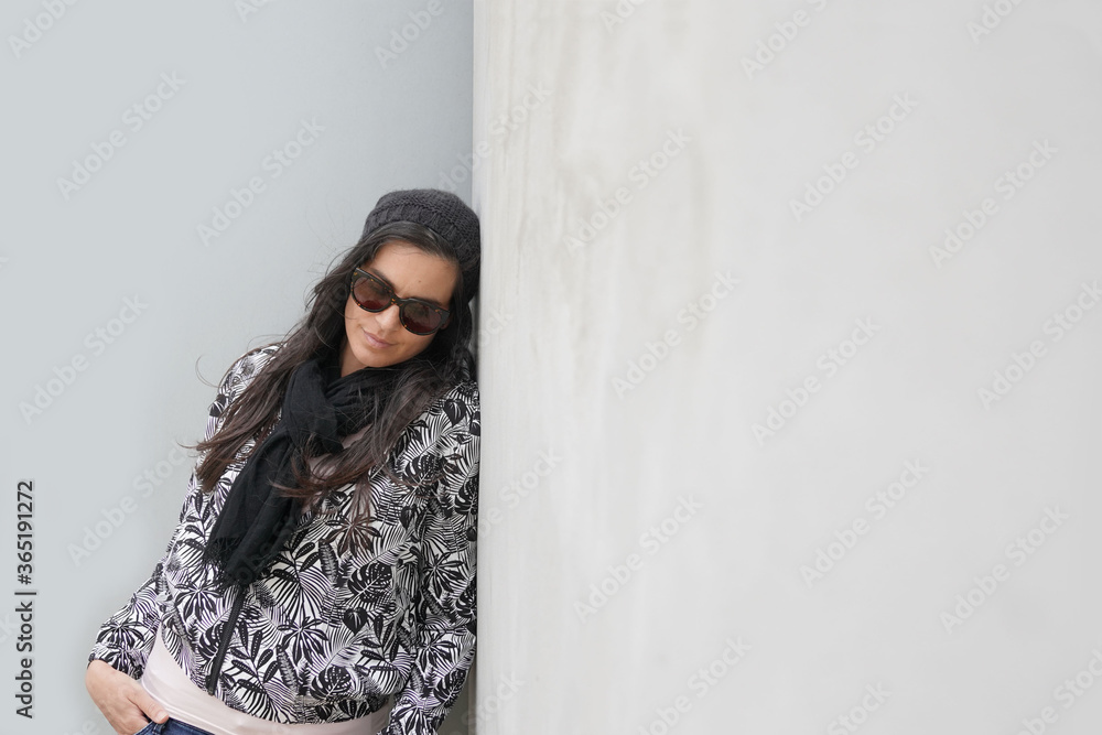 trendy woman wearing black sunglasses and scarf standing on concrete wall, isolated trendy woman wearing black sunglasses and scarf standing on concrete wall, isolated