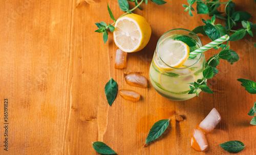 Refreshing summer detox lemonade with cucumber, lemon and mint in a glass on a wooden table top view