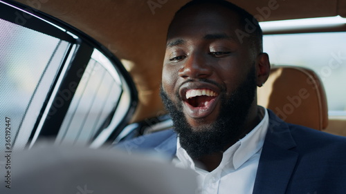 Portrait of cheerful african business man looking ficancial documants at car. © stockbusters