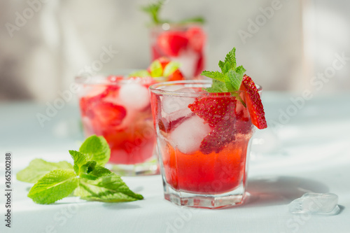 Glasses of strawberry soda drink on light blue background. Summer healthy detox lemonade, cocktail or another drink background. Nonalcoholic drinks, super food, vegetarian or healthy diet concept.