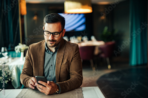 Handsome man using smart phone in the restaurant, portrait, copy space.