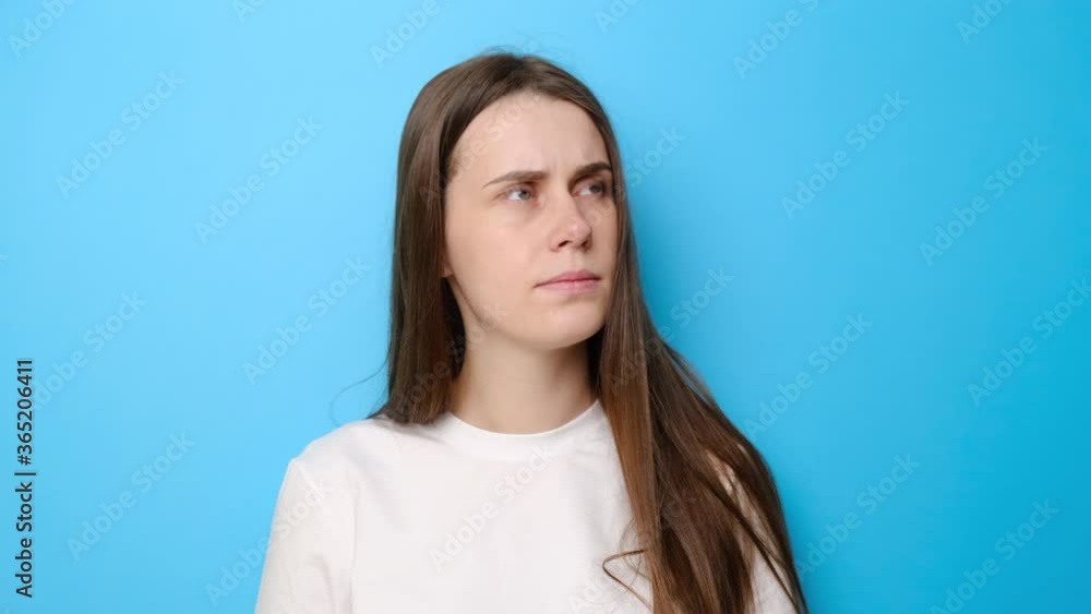 Confused young woman isolated on blue studio background looking around as if searching problem solution, thinking idea with doubtful uncertain expression, dressed in white t-shirt, difficult decision Confused young woman isolated on blue studio background looking around as if searching problem solution, thinking idea with doubtful uncertain expression, dressed in white t-shirt, difficult decision