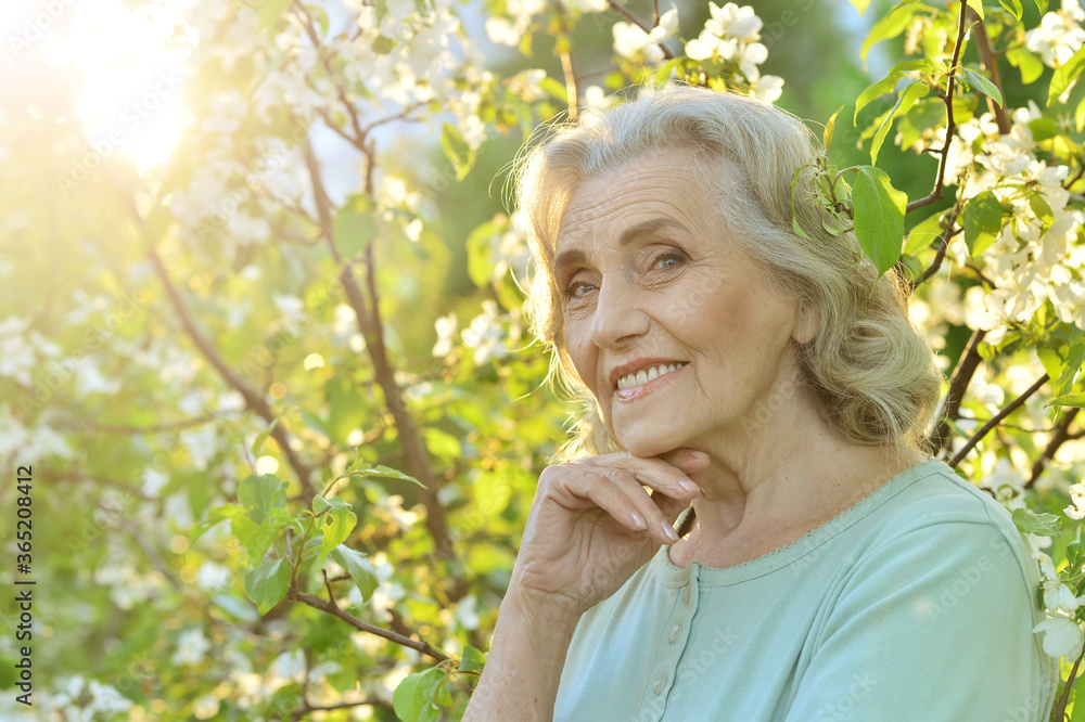 Portrait of beautiful senior woman posing near blooming tree Portrait of beautiful senior woman posing near blooming tree
