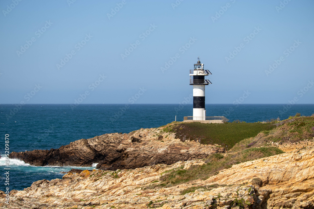 Black and white lighthouse fitted with solar panels on the Illa Pancha in Lugo Spain