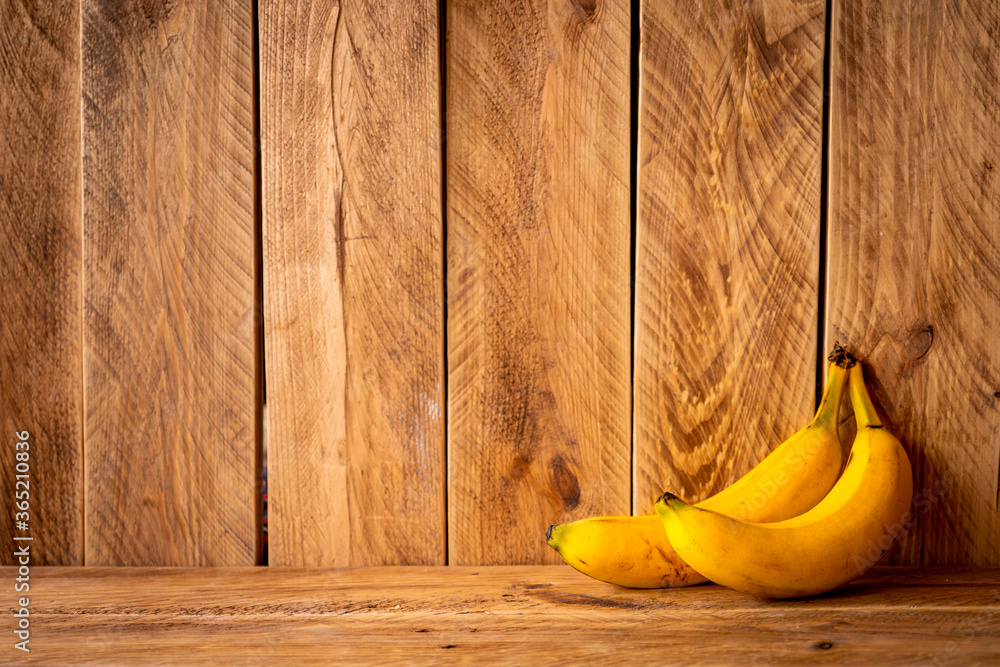 Brown wooden wall with two yellow bananas and copy space - obrazy, fototapety, plakaty 
