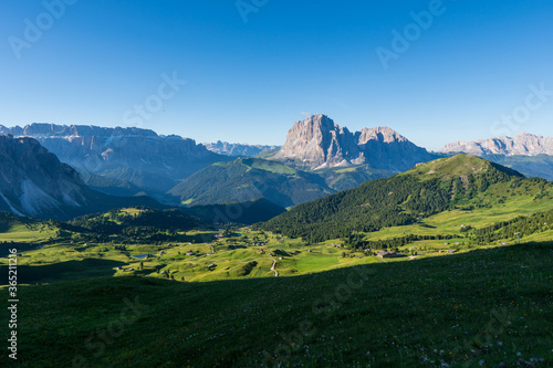 Epic mountainlandscape in Puez Odle  Dolomiti   Dolomites Alps in Italy  Seceda area  with Sass Rigais in background  small traditional cottages in green meadow and hiking trail path. Active vacation.
