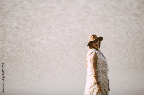 Fototapeta Naklejka Na Ścianę i Meble -  A blonde bohemian woman with a hat outdoors in a lake background