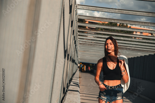 Giovane ragazza cammina sorridendo con aria spensierata mentre indossa un top nero e jeans in una localit   metropolitana d estate
