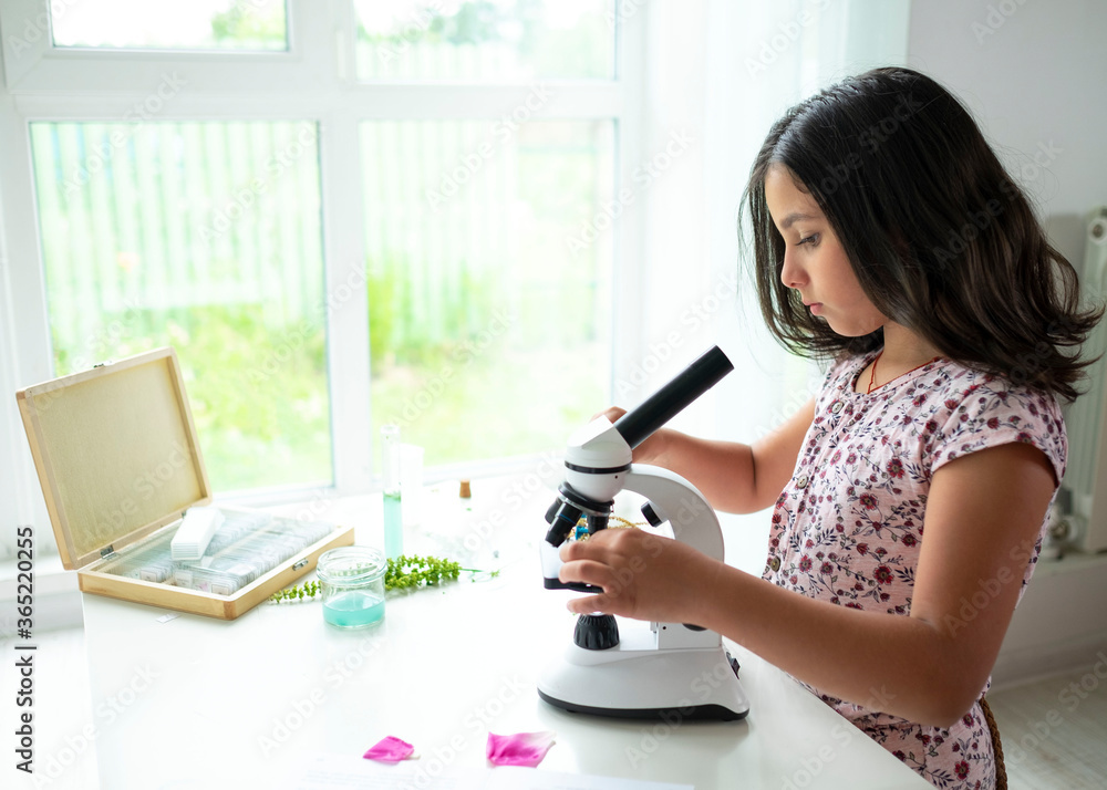 Pretty blonde little girl working with test tube and microscope. The kid learning science in the school laboratory or at home. Child looking make experiment with microscope on the table. Pretty blonde little girl working with test tube and microscope. The kid learning science in the school laboratory or at home. Child looking make experiment with microscope on the table.