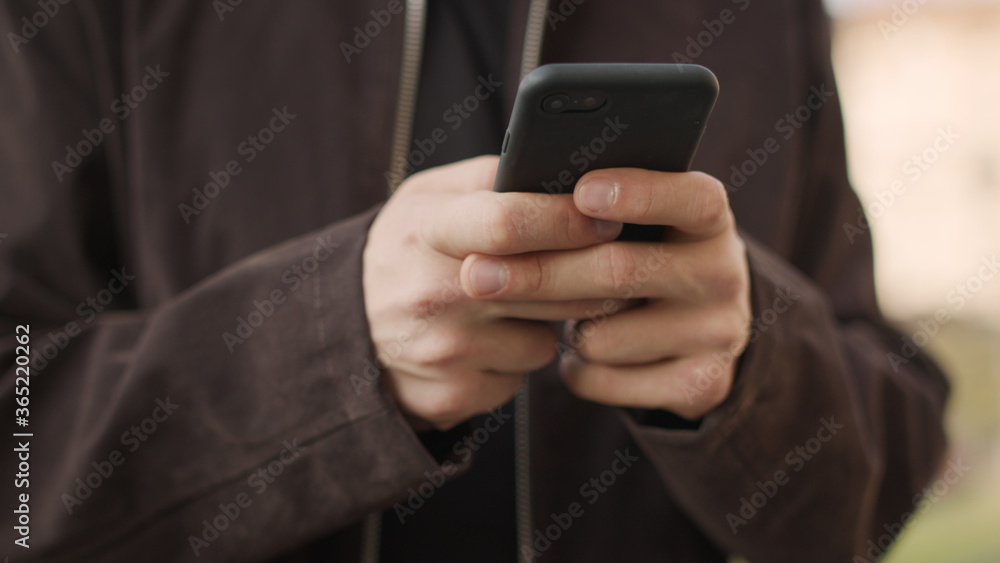 Male hands using mobile phone outdoors. Unknown guy texting phone outside Male hands using mobile phone outdoors. Unknown guy texting phone outside