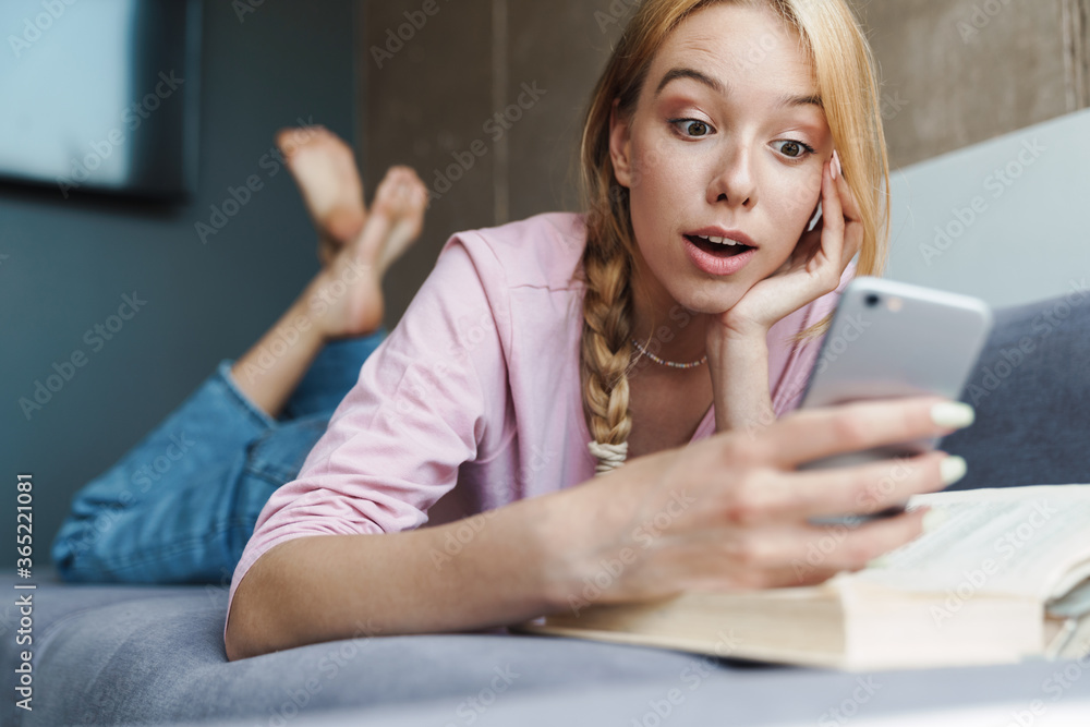 Photo of astonished nice woman using mobile phone while lying on couch Photo of astonished nice woman using mobile phone while lying on couch