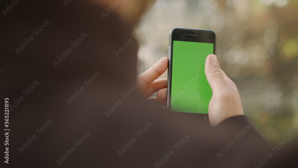 Man scrolling smartphone green screen. Guy surfing internet mock up cellphone