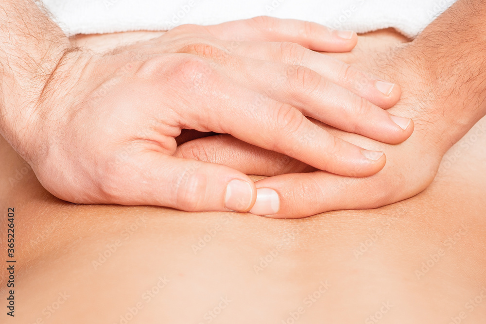 Close up of hands of massage therapist doing back massage on back of young man. Close up of hands of massage therapist doing back massage on back of young man.