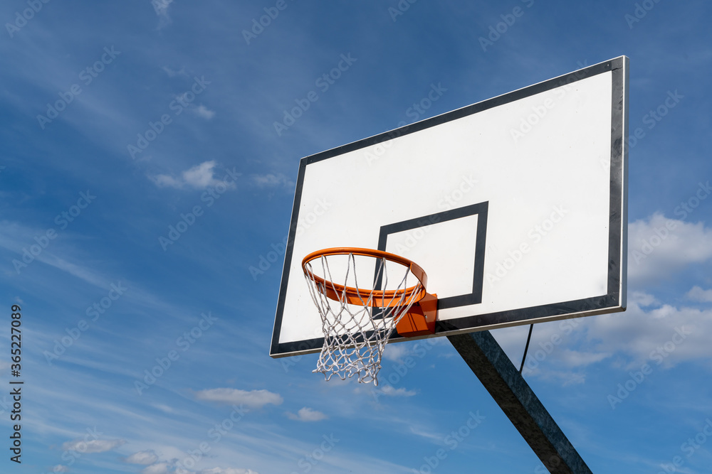 isolated view of a basketball hoop and backboard under an expressive blue sky