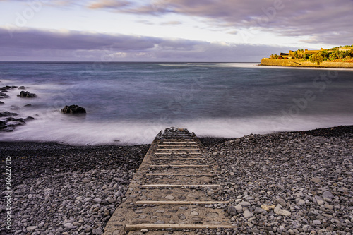 La Caleta of Interian pebbles beach, with sunset sunlight and grey clouds, long exposure, Tenerife, Canary islands, Spain photo