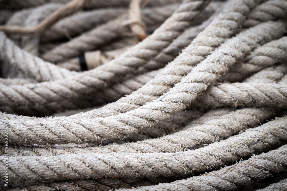 Mooring rope old frayed boat then piled on the floor.  Ship or rock climbing tackle.