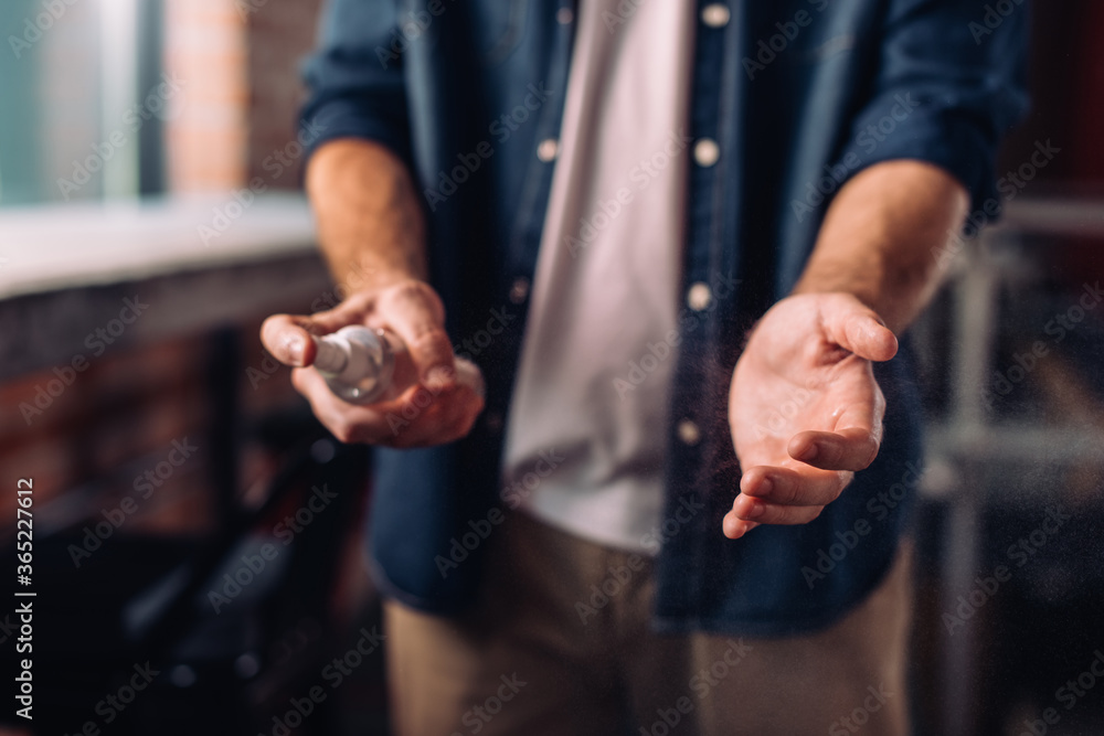 cropped view of businessman spraying sanitizer on hand