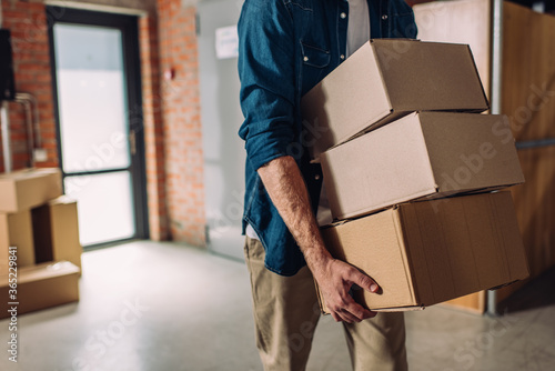selective focus of businessman holding boxes and moving in new office © LIGHTFIELD STUDIOS