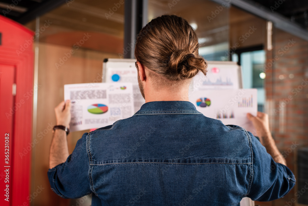 back view of businessman touching charts and graphs in office back view of businessman touching charts and graphs in office