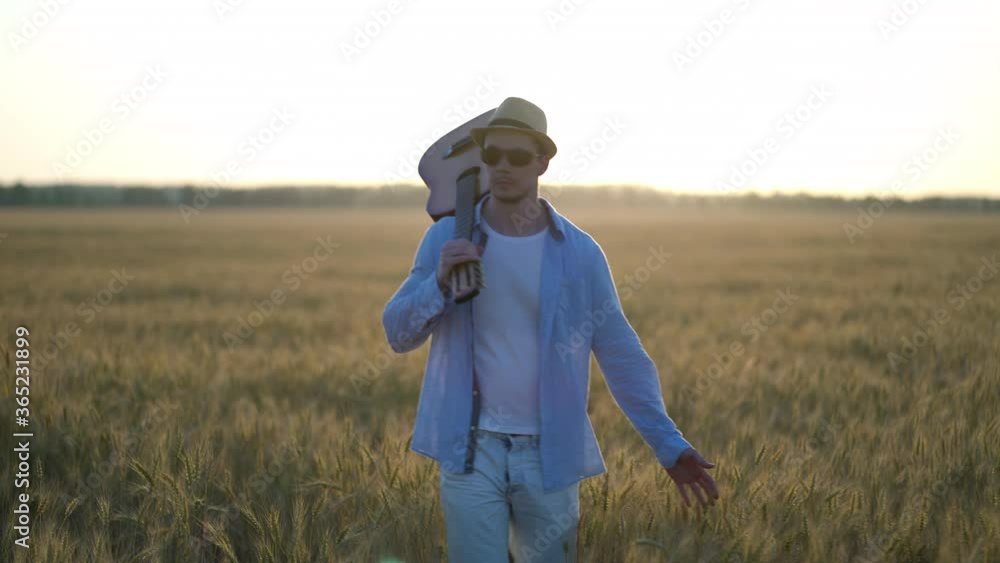 Young Man Walking with Guitar in Wheat Field Young Man Walking with Guitar in Wheat Field