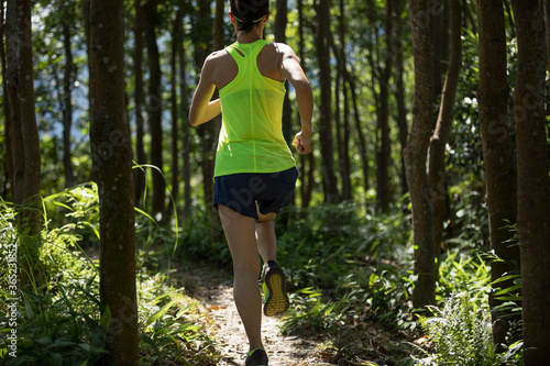 Fitness woman trail runner running in tropical forest