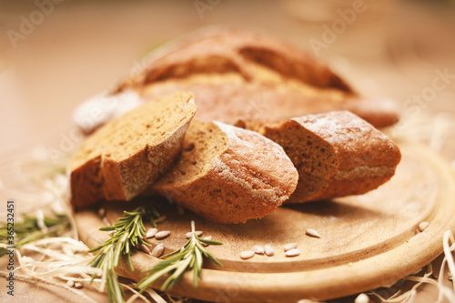 Sliced homemade bread with rosemary on wooden cutting board 