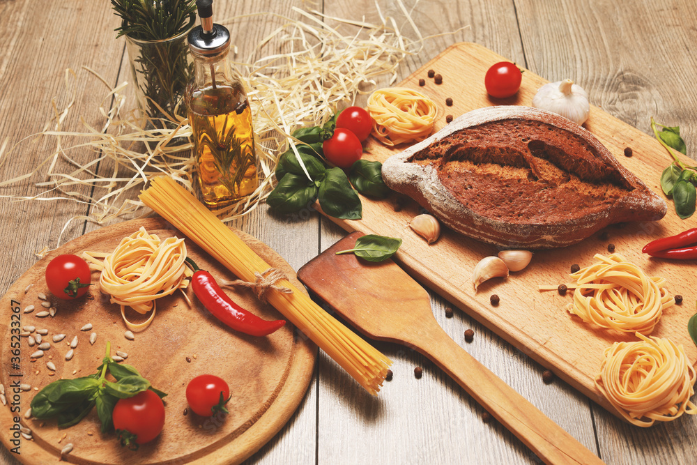 close up view on bread with red pepper,garlic,basil,spaghetti,sunflower oil and rosemary on wooden board.