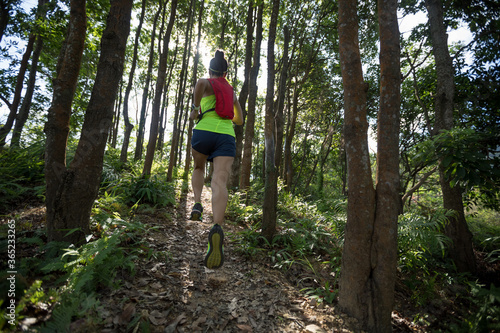 Fitness woman trail runner running in tropical forest