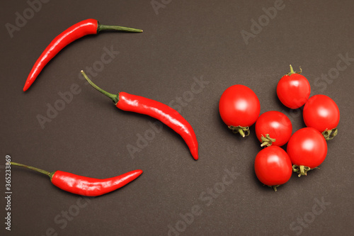 top view of cherry tomatoes and red chili pepper with copy space isolated on black background. Flat lay.