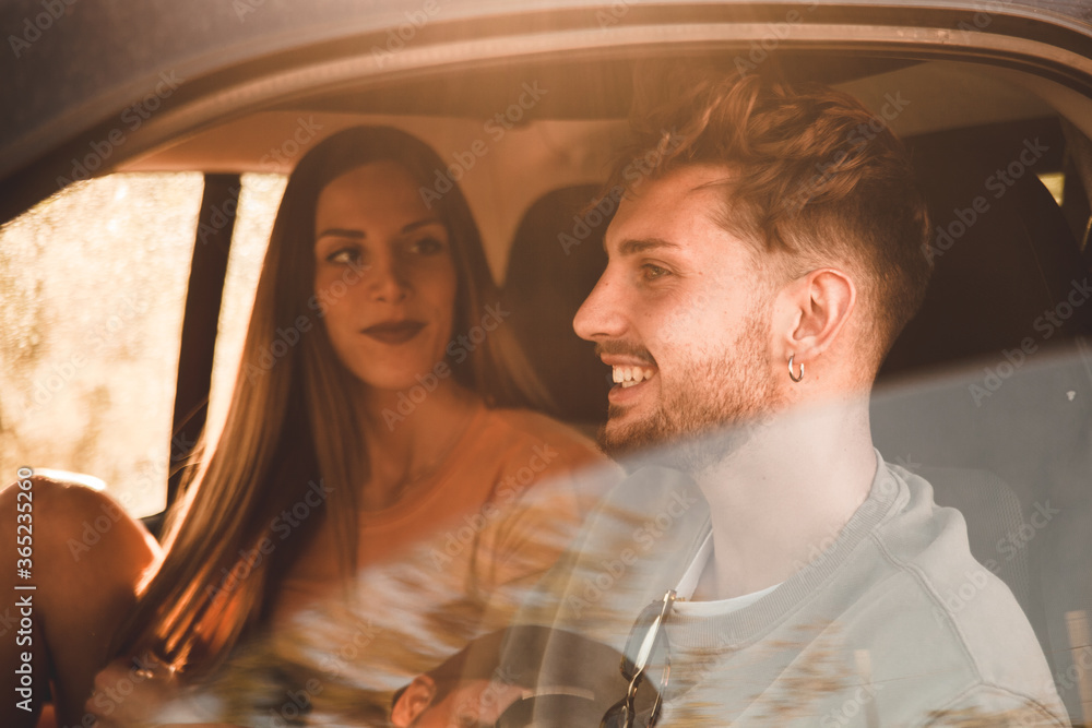 Momento di relax di due fidanzati in auto mentre si guardano con aria complice e spensierata durante un viaggio