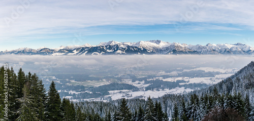 Amazing panoramic View to snowy Mountain Range above foggy cloud layer. View from Rangiswangerhorn to Illertal, Allgau, Bavaria, Germany.