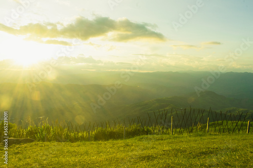 Sunset and mountains interspersed with green grass