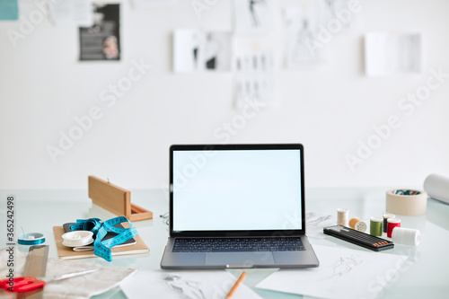 Workplace of fashion designer, laptop with empty screen on desk in office. Photo for ad educational courses or clothing © Georgii