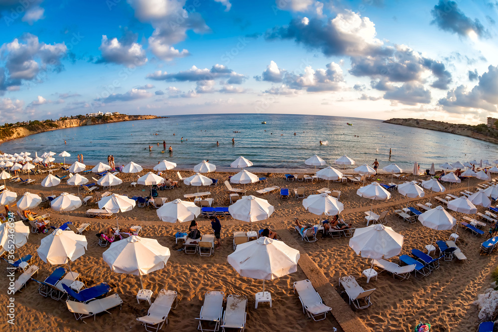 Rows of beach lounges and sun umbrellas on a Coral Bay beach near Peyia village.