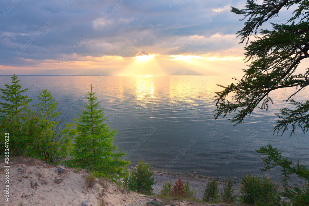 Baikal Lake. Beautiful summer landscape with a sandy beach of the Olkhon Island and sunset with colorful clouds over water with reflection. Natural background Baikal Lake. Beautiful summer landscape with a sandy beach of the Olkhon Island and sunset with colorful clouds over water with reflection. Natural background