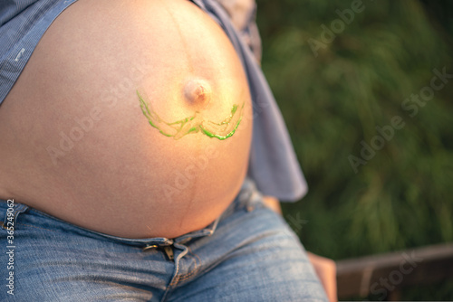 Pregnant woman's tummy with painted mustache