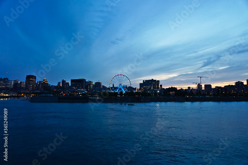 A skyline of Montreal Old Port and Downtown at the twilight blue hour. Foreground is Saint Laurent river.