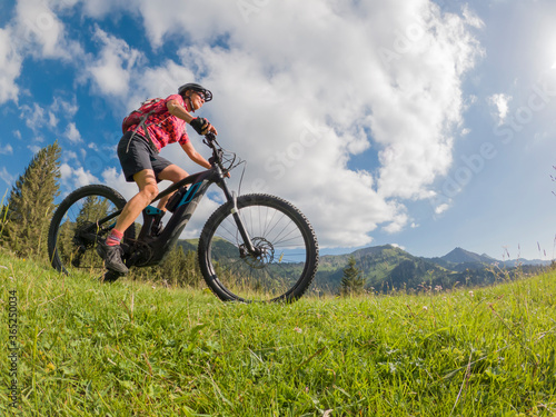 active senior woman riding her electric mountain bike in the Allgau Alps near city of Immenstadt  Alg  u  Bavaria  Germany