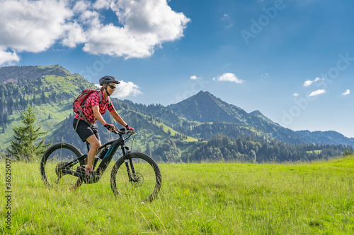 active senior woman riding her electric mountain bike in the Allgau Alps near city of Immenstadt, Algäu, Bavaria, Germany