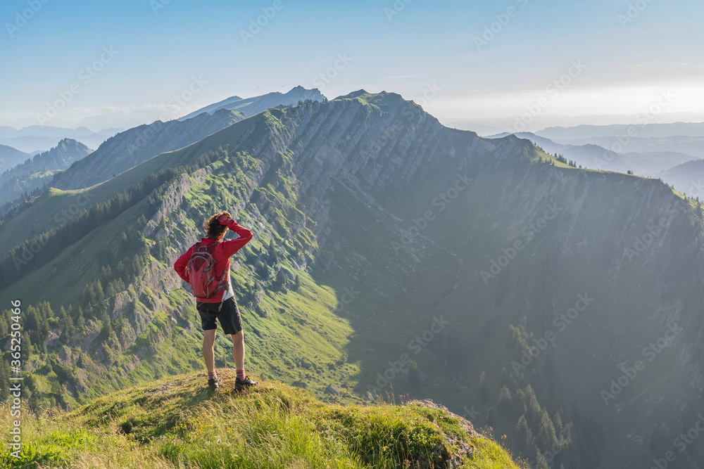 pretty senior woman resting during a hike in the early evening in warm dawn light on the ridge of the Nagelfluh chain in the Allgau Alps near Immenstadt, Bavaria, Germany